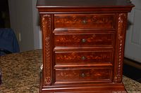 Front view of the jewelry box showing carved hardwood details and four visible drawers.