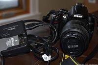 Nikon D5000 camera body with attached 18-55mm VR lens and Nikon MH-24 charger cable