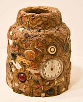 Front view of the memory jar showing the embedded watch face and various small buttons and decorations.
