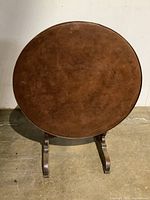 Top view showing the round leather surface of the flip top table with signs of wear and patina.