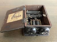 Open wooden case showing internal coils, wiring terminals, and wiring diagram sticker inside lid.