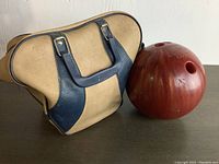 Photo of the vintage Brunswick Mixer bowling ball alongside the tan and blue carrying bag.