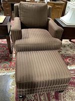 Front view of brown upholstered chair with matching ottoman on a patterned rug