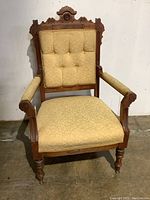 Front view of solid wood East Lake style armchair with beige upholstered seat and button tufted backrest.