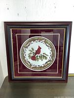 Square framed cardinal bird artwork with maroon mat and ornate dark wooden frame photographed in front view.