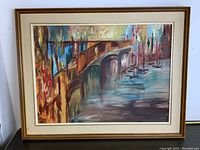 Framed oil painting showing abstract bridge and waterfront scene in warm and cool tones.