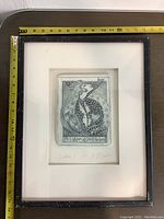 Photo showing framed tile art with measuring tape indicating size, black frame with visible wear and chipping.