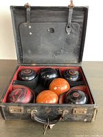 Photo of open carrying case showing six black bocci balls, two orange, and one red ball