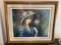 Framed vintage lithograph art print featuring a Victorian woman with a large feathered hat and a man in a top hat behind her.