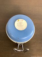 Top view of the vintage wall-mounted scale showing blue plastic casing and circular label.
