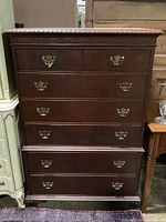 Full front view of wooden chest of drawers showing five drawers and brass handles