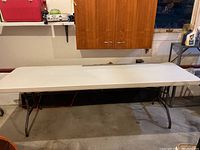 Photo of the top surface of the white folding table with resin top in a garage setting.