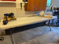 Full view of the 8-foot folding table with various objects placed on top, showing resin surface and metal legs.