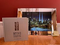 Illuminated mirrored NYC wall art with twin towers tribute lights and commemorative 9/11 photo book boxed next to it