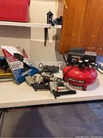 Overview of all items on workbench: air compressor, pneumatic tools, shop light and weatherstripping