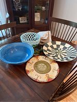 Photo showing the full assortment of ceramic platters, bowls, glassware, and table runners on a wooden dining table.