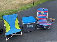 Two beach chairs and Igloo cooler visible on pavement with grass background