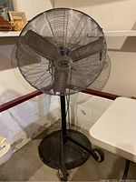 Front and angled view of the commercial floor fan showing full fan head and stand.