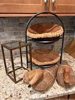 Lot showing decorative wrought iron stand with two wooden bowls, glass and brass mini plant stand, three rush reed duck decoys on a kitchen counter.