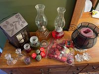 Full view of all candles, candle holders and assorted candles on wooden dresser surface to show lot contents