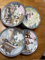 Top view of stacked Jingdezhen porcelain plates depicting hand-painted scenes of Chinese figures and landscapes from Beauties of the Red Mansion