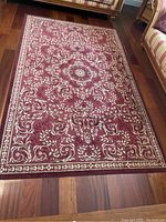 5x8 red area rug with floral and medallion patterns on hardwood flooring