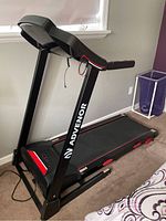 Side and angled view of Advenor treadmill showing foldable sturdy black frame with red accents and the running belt.