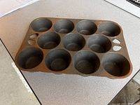 Full view of vintage Wagner Ware cast iron muffin pan with ten muffin cups and signs of age-related wear