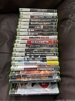 Stack of 19 Xbox 360 games showing titles from Call of Duty, Gears of War, Lord of the Rings, Red Dead Redemption and others, in original cases.