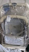 Photo of the unopened child's stroller wrapped in plastic showing handlebar and padded seat area with label.