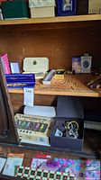 Shelf with boxed essential oils, jewelry boxes with costume jewelry, perfume sample boxes, and wooden fan handles