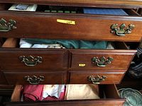Open wooden drawers showing folded table linens stored inside with antique brass handles visible.