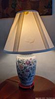 Photo of one Asian style ginger jar lamp with a cream fabric shade showing visible wear and some stains.