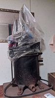 Full view of the cast iron sausage press with plastic covering and attached grinder motor on wooden base.