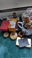 Photo showing assorted decorative boxes, small ceramic jars, white ceramic water pitcher with floral decorations, and small stoneware vases.