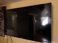 Photo of Toshiba 51-inch flat screen TV mounted on wall, showing front view with reflections on screen.