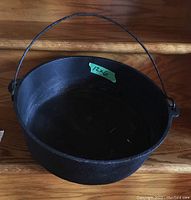 Top view of round cast iron cauldron showing interior and green label with dimensions 12x6.