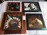 Four framed items laid flat on a surface: Rolling Stones 12x5 LP cover, Bob Marley signed charcoal drawing, Crowbar Larger Than Life LP cover, and His Masters Voice print.