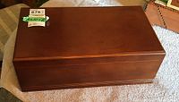 Closed rectangular wooden humidor box with smooth brown finish and labels on top corner.