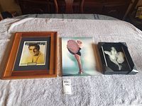 Three framed items on a bed: the Elvis Presley framed print on the left, Marilyn Monroe hologram cover print in the middle, and black and white Marilyn Monroe hologram on the right.