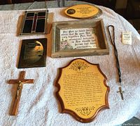 Photo of all six items displayed on a blanket: stained glass cross, wood crucifix, framed inspirational saying, wood plaques, rosary