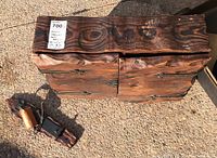 Top-down view of rustic wooden cabinet with copper dinner bell placed on the ground showing natural wood grain and patina.