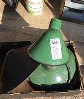 Green enamel conical workshop light shade with attached working light and wiring in a box with black metal lamp shade.