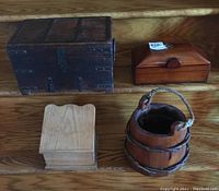 Four wooden items displayed: large dark box with metal detailing, recipe box, wood box with embedded coin, small ferkin bucket with rope handle.