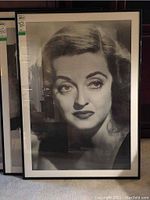 Front view of the large framed black and white Bette Davis poster showing her face