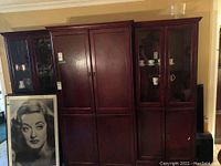 Three piece dark wood cabinet entertainment unit consisting of two curio cabinets and a central entertainment unit, shown assembled and fully upright.