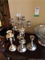 Overall front view of candelabra with five candle holders at center back and four candle holders arranged in front of it, including two with crystal decorations.