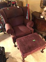 Wing back chair and matching ottoman in striped upholstery with wooden claw feet, side view.