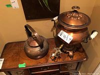 Photo showing the copper kettle with hinged handle and the copper samovar with ceramic handles on a wooden surface