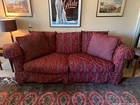 Front view of Rowe Furniture fabric couch with red and burgundy floral and striped upholstery, two large cushions, rolled arms, and skirted base.